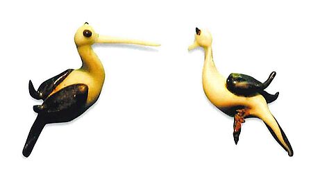 2 glazen ooievaars met pennetjes in hun buik, de meeste rozetjes hebben resten van pennetjes.