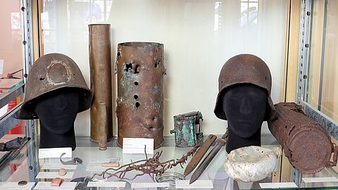 Helmen, scherven en munitie in een vitrine.